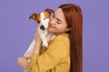 Woman hugging her cute Jack Russell Terrier dog on violet background