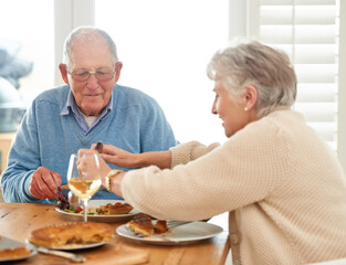 Love, help and senior couple eating lunch together in the dining room of their modern home. Happy,...