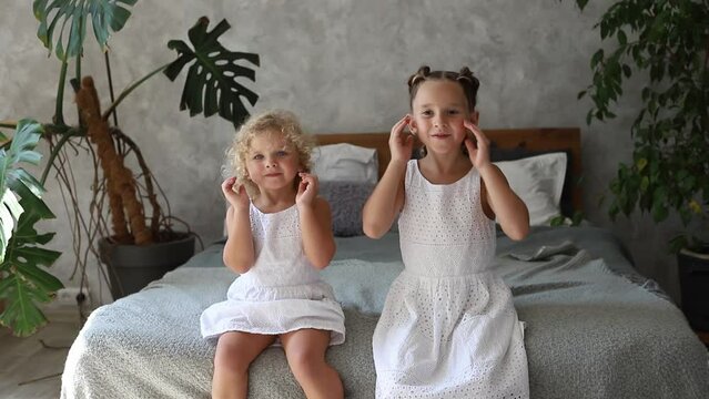 Two little sisters playing funny faces touching cheeks blowing wind, closing eyes. Lifestyle family funny content