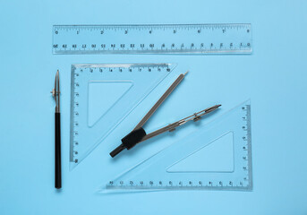 Different rulers and compass on light blue background, flat lay