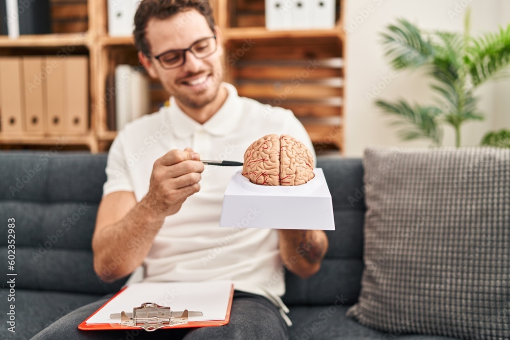 Sticker Young hispanic man psychology holding brain at psychology center