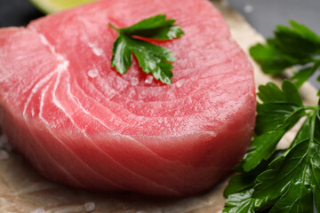 Fresh raw tuna fillet with sea salt and parsley on table, closeup