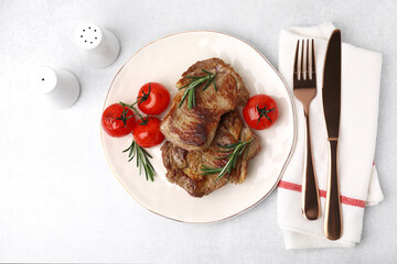 Delicious fried meat with rosemary and tomatoes served on light grey table, flat lay