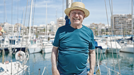 Senior grey-haired man tourist wearing summer hat smiling at boat