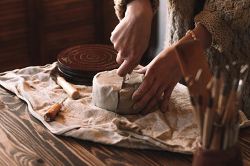 A female sculptor kneading clay,making ceramics in a home workshop,hands close-up.Small business,entrepreneurship,hobby, leisure,sustainability concept.