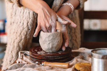 Fototapeta premium Female sculptor making clay mug in a home workshop,hands close-up.Small business,entrepreneurship,hobby, leisure concept.
