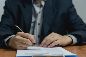 Businessman holding a pen signing a document, law ,job search, write a personal contract on desk.