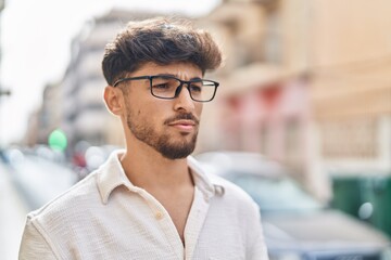 Young arab man wearing glasses with serious expression at street