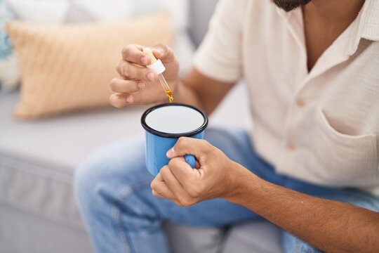 Young Arab Man Pouring Liquid On Coffee Sitting On Sofa At Home