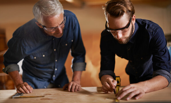 Teamwork, carpenter and apprentice in workshop, wood measurement and designer furniture manufacturing. Mentorship, carpentry and men at sustainable business, teaching and learning with design project