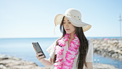 Fototapeta premium Young chinese woman tourist using smartphone at seaside