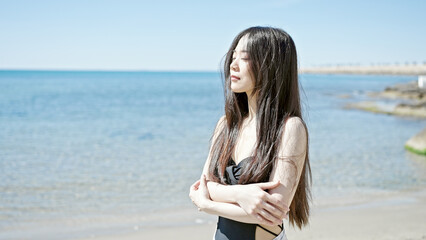Young chinese woman tourist wearing swimsuit breathing at seaside