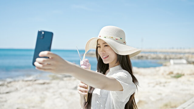 Young chinese woman tourist make selfie by smartphone eating ice cream at seaside