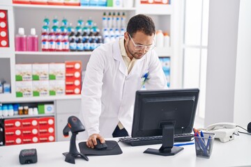 Young man pharmacist using computer working at pharmacy