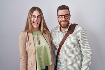 Young couple standing over white background winking looking at the camera with sexy expression, cheerful and happy face.
