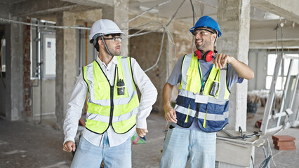 Two men builders smiling confident dancing at construction site