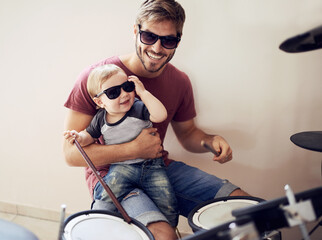 Obraz na płótnie Canvas Cool father, baby sunglasses and drummer musician with music development and child learning. Home, happiness and dad with youth drumming lesson with smile, love and parent care at a family house