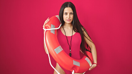 Young beautiful hispanic woman lifeguard holding lifeguard float over isolated red background