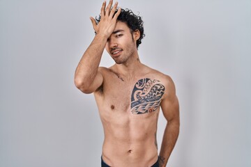 Fototapeta premium Hispanic man standing shirtless surprised with hand on head for mistake, remember error. forgot, bad memory concept.