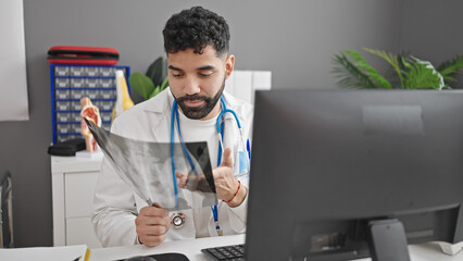 Fototapeta na wymiar Young hispanic man doctor looking xray using computer at clinic