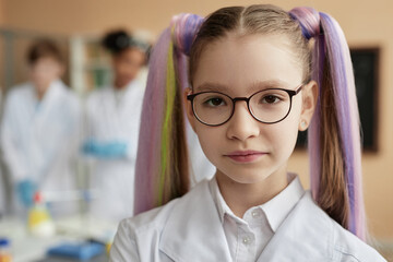 Closeup portrait of cute teen schoolgirl with pigtails wearing lab coat in science class and...