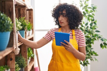 Young middle eastern woman florist using touchpad at florist