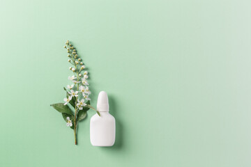 Seasonal allergy concept, spring blooming branches tree and mock up nasal spray white bottle on...