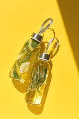 Water drink detox with lemon and mint leaves, and rosemary, shadow at sunlight on Cleansing and refreshing drinks. Glass reusable water bottles, aesthetic life style, flat lay, wellness trend