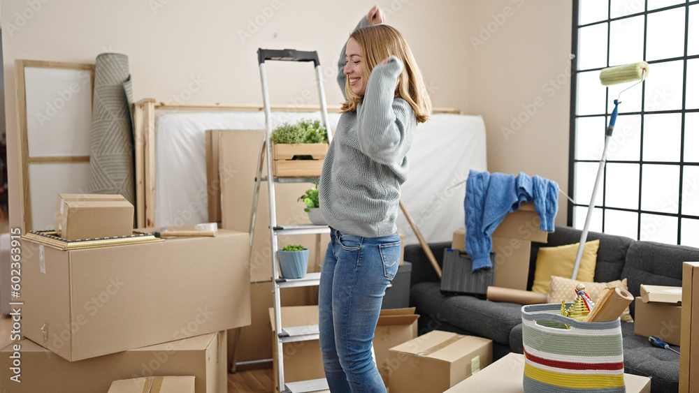 Poster young blonde woman smiling confident dancing at new home