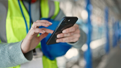 Young blonde woman builder using smartphone at street