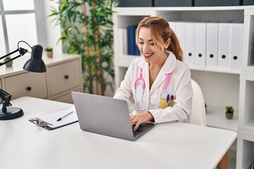 Young woman wearing doctor uniform using laptop working at clinic