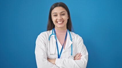 Young beautiful hispanic woman doctor standing with arms crossed gesture saying yes with head over isolated blue background