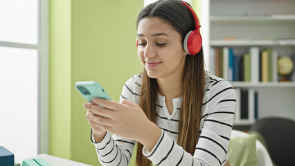 Young beautiful hispanic woman student smiling confident listening to music at library university