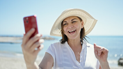 Fototapeta premium Middle age hispanic woman tourist smiling confident make selfie with smartphone at the beach