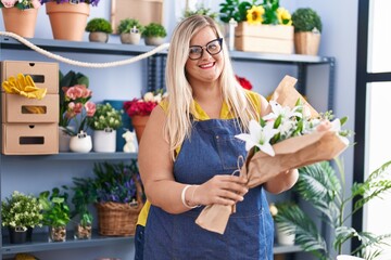 Young woman florist holding bouquet of flowers at florist