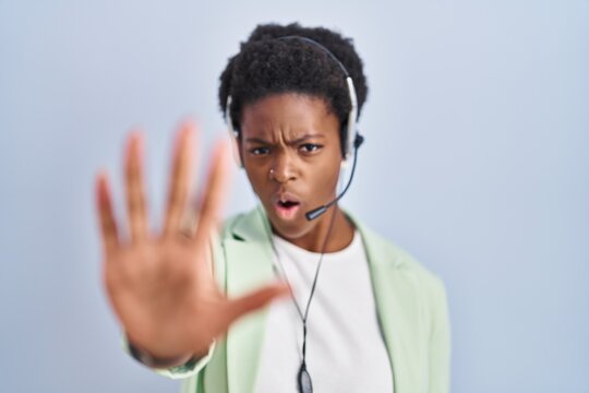 African american woman wearing call center agent headset doing stop gesture with hands palms, angry and frustration expression