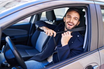 Young hispanic man smiling confident wearing car belt at street