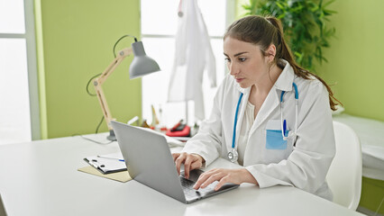 Young beautiful hispanic woman doctor using laptop working at clinic