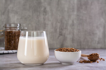 Vegan dairy-free buckwheat milk in a glass and cereals in a bowl on the table