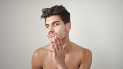 Fototapeta premium Young hispanic man combing bear with hand over isolated white background