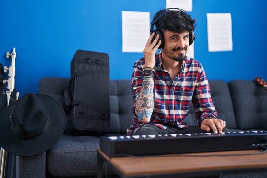 Young hispanic man musician smiling confident playing piano keyboard at music studio