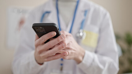 Obraz na płótnie Canvas Young hispanic man doctor using smartphone at clinic