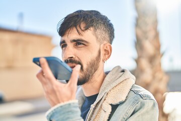 Young hispanic man talking on the smartphone at street