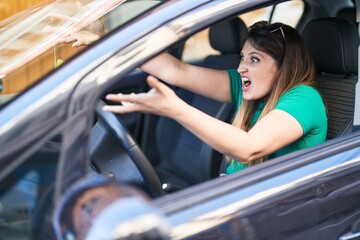Fototapeta na wymiar Young hispanic woman furious driving car at street