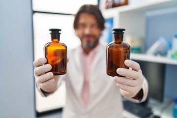 Middle age man scientist holding bottles at laboratory