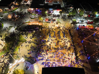 A Music Festival looking at the crowds of people enjoying music at night on an outdoor stage as seen from a UAV Drone Aerial Shot