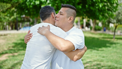 Fototapeta premium Two men hugging each other with relaxed expression at park