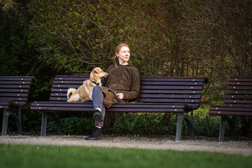 Beautiful blonde girl with dog walking in the park