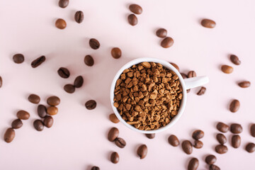 Dry granules of instant coffee in a cup on a pink background top view