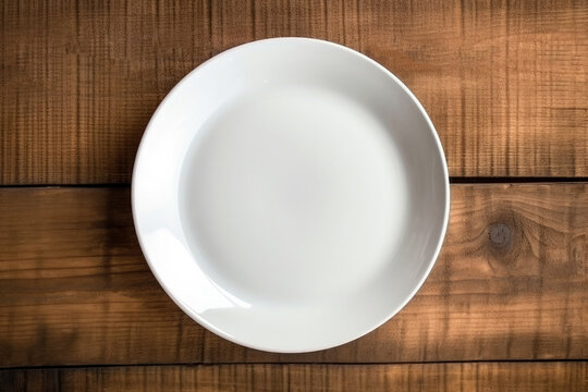 Empty white plate on wooden background. Top view. Copy space.